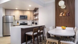Una cocina moderna con una isla central, electrodomésticos integrados y un comedor con una mesa redonda y sillas.