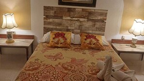 Une chambre d’hôtel avec un lit, deux tables de chevet, un tableau au-dessus du lit et un mur orné d’un motif texturé.