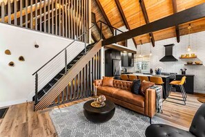 Ein modernes Interieur mit Treppe, einer Ledersofa, einem Essbereich und einer Küche.