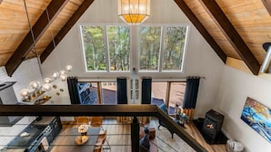 Ett rum i loftstil med ett stort fönster, en öppen spis och en hängande lampa.