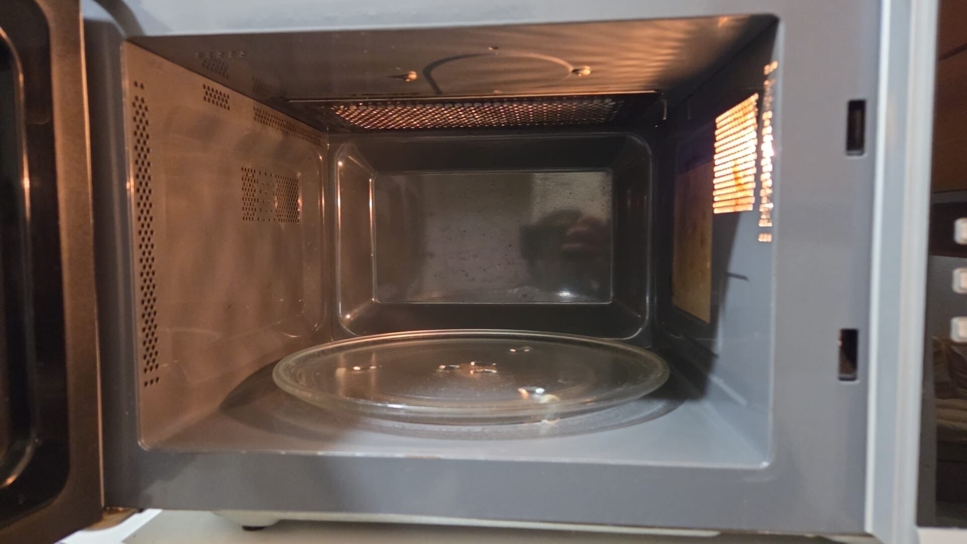 An empty microwave with a clear glass plate inside.