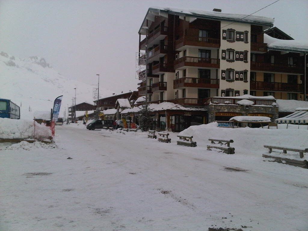 Eine verschneite Straße mit Gebäuden, Bänken und einem Bus.