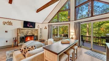 A cozy living room with a stone fireplace, a large window, and a deck.