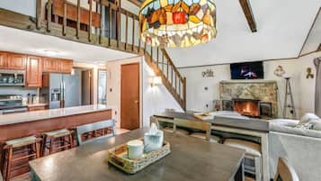A spacious living area with a wooden staircase, a fireplace, and a kitchen with wooden cabinets.