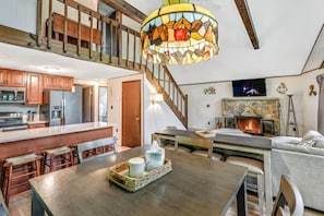 Ein geräumiger Wohnbereich mit einer Holztreppe, einem Kamin und einer Küche mit Holzausstattung.