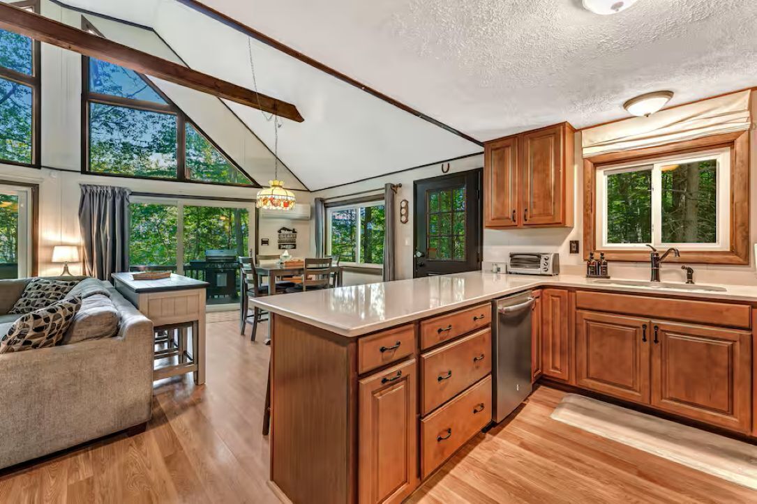 A spacious kitchen with wooden cabinets, a large island, and a dining area with a sofa and table.