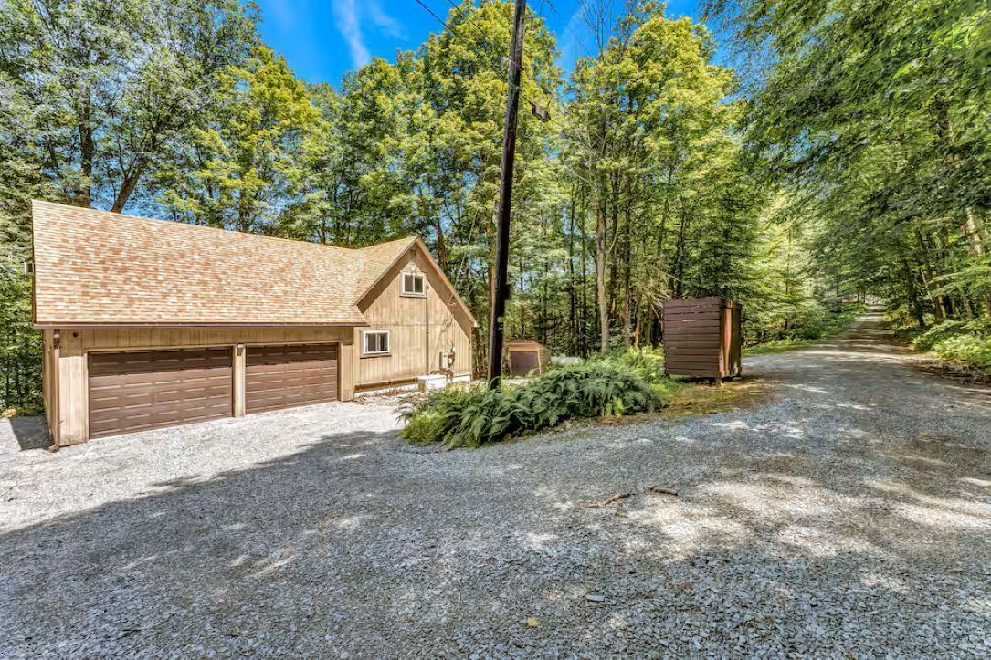 A wooden cabin with a garage, surrounded by a forest.