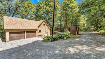 A wooden cabin with a garage, surrounded by a forest.