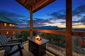 A wooden deck with a fire pit, a chair, and a view of mountains. - New Cabin!! Views, Hot-tub, Indoor Heated Pool, Arcade Games Near Pigeon Forge (Sevierville)