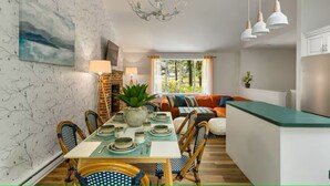 Comedor con una mesa dispuesta para cuatro personas, rodeada de sillas de mimbre, un ventilador de techo y lámparas colgantes.
