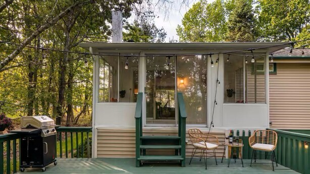 Un espacio al aire libre techado con una parrilla, sillas y una mesa.