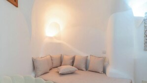 A bedroom with a bed, pillows, a wall-mounted light, and a partial view of a window. - Elite Collection - Villa Emerald Aura  (Arzachena)
