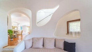 Un intérieur moderne comprenant un canapé, un coin repas et une cuisine visible à travers une arche.