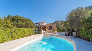 A pool with a stone house in the background, surrounded by greenery. - Elite Collection - Villa Emerald Aura  (Arzachena)