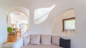 A modern interior with a sofa, a dining area, and a kitchen visible through an archway. - Elite Collection - Villa Emerald Aura  (Arzachena)