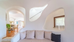 A modern interior with a sofa, a dining area, and a kitchen visible through an archway. - Elite Collection - Villa Emerald Aura  (Arzachena)