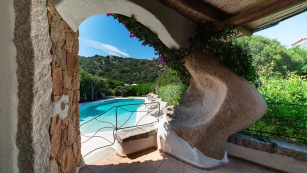 A stone archway leading to a swimming pool with a view of a lush green hillside. - Elite Collection - Villa Emerald Aura  (Arzachena)