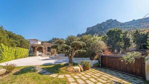 A courtyard with a stone pathway, a tree, and a building with a tiled roof. - Elite Collection - Villa Emerald Aura  (Arzachena)