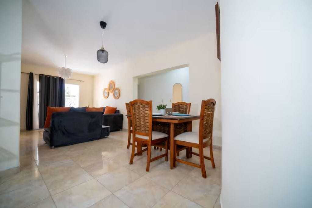 Uma área de refeições com mesa, cadeiras, um sofá e uma luminária no teto.