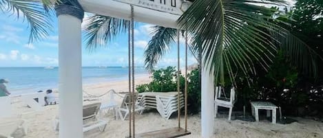 En strand med gyngestativ, et skilt med teksten 'ZOHO' og en palme.
