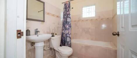 A bathroom with a pedestal sink, toilet, bathtub, and a shower curtain.