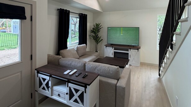 A modern living room with a sofa, coffee table, TV, and ceiling fan.