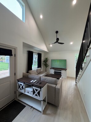 Una sala de estar moderna con sofá, mesa de centro, televisor y ventilador de techo.