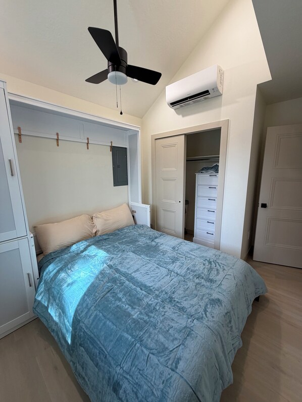 Un dormitorio con cama, ventilador de techo, unidad de aire acondicionado y vestidor.