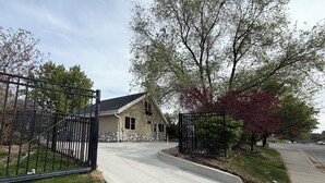 A residential house with a gated driveway, a stone foundation, and a lawn.