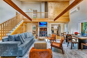 A spacious living area with a staircase, a fireplace, and a dining area. - Summitgrove Cabin w/ Hot tub, Game Room &OutdoorTV (Long Pond)