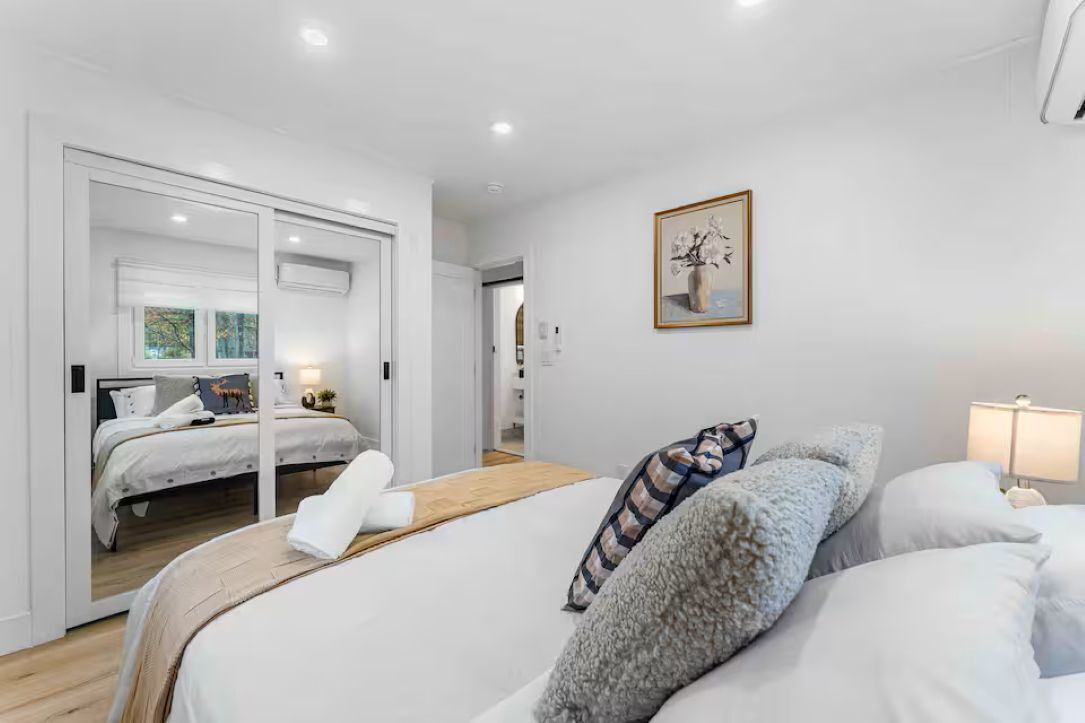 A modern bedroom with a large bed, a smaller bed, and a walk-in closet.