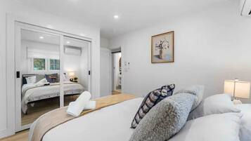A modern bedroom with a large bed, a smaller bed, and a walk-in closet.