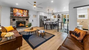 Una sala de estar moderna con chimenea, comedor y cocina.