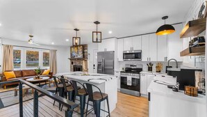 Una cocina moderna con armarios blancos, electrodomésticos de acero inoxidable y una isla central con taburetes de bar.