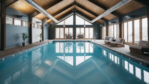 Una piscina con vigas de madera y ventanas amplias.