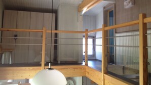 Een kamer met een houten plafond, een houten vloer, een raam en een klok.