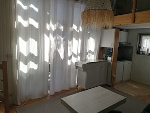 A kitchen with white cabinets, a wooden countertop, and a hanging light fixture.