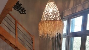Een kamer met een houten trap, een witte tafel en een groot raam met uitzicht op een terras.