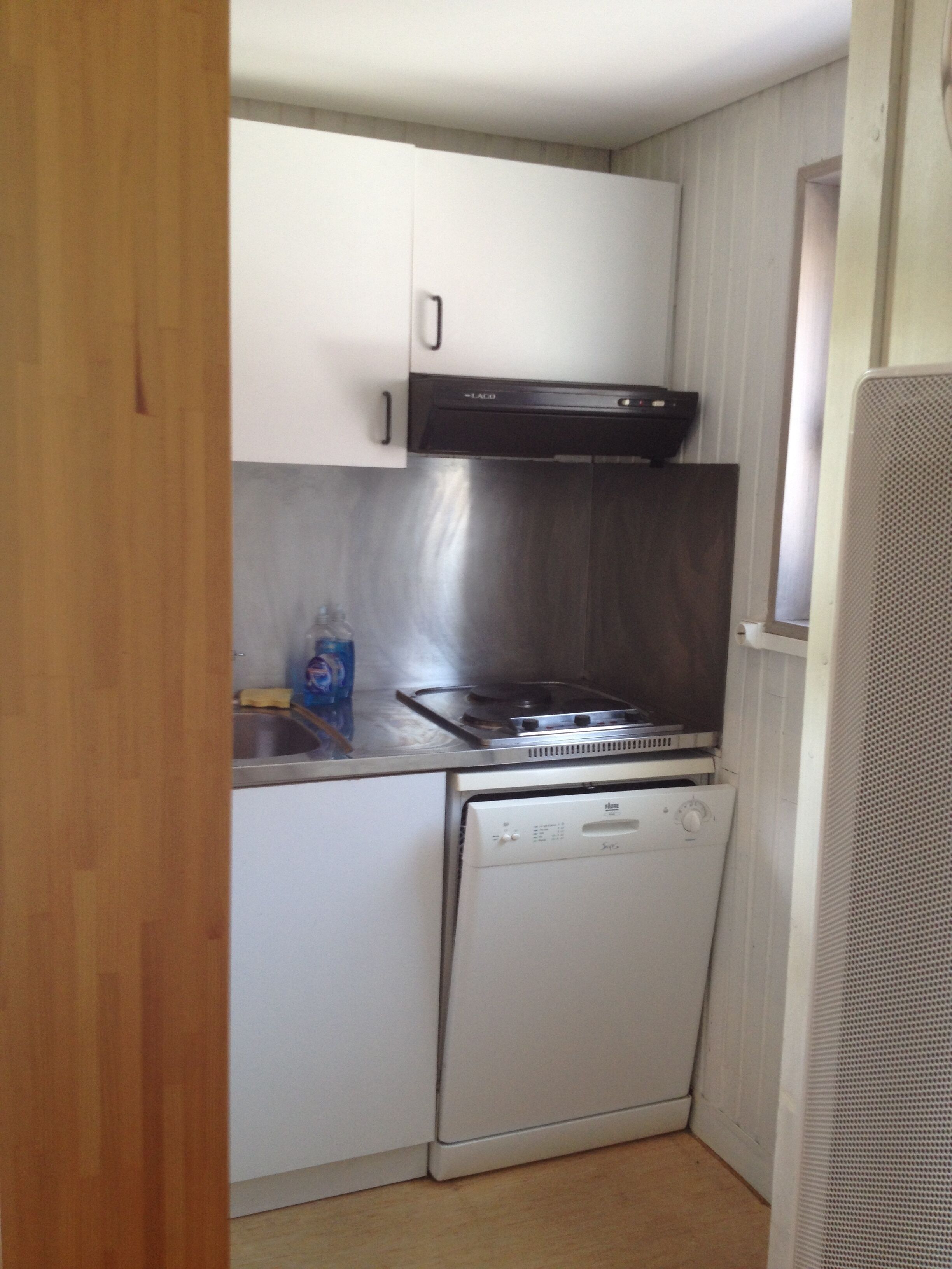 A compact kitchen with a stove, dishwasher, and cabinets.