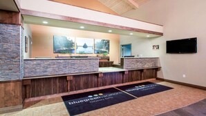 A reception area with a stone wall, wooden reception desk, and a flat-screen TV mounted on the wall. - Wisconsin Dells Family Stay with Water Park Access & Spacious 2BR Suite (Wisconsin Dells)