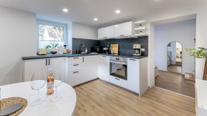 Een moderne keuken met witte kasten, een inbouwoven en een raam.