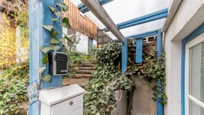Een beveiligingscodekast bevestigd aan een blauwe paal, een witte elektriciteitsdoos en een gebouw met blauwe accenten en een houten trap.