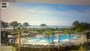 A resort with a large pool area, palm trees, and a view of the ocean. - Ocean Front View Hilton Head Island 2 bedroom Condo sleeps 8 w/ Golf access (Hilton Head Island)