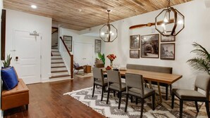 A dining area with a wooden table, chairs, and a patterned rug. - 10BR Downtown Savannah Combo | Walk to Nightlife (Savannah)