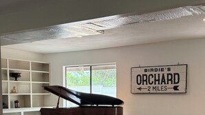 Ein Wohnzimmer mit einem roten Sofa, einem weißen Sofa, einem Klavier und einem Schild mit der Aufschrift 'Birdie's Orchard 2 miles'.