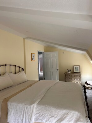 Ein Schlafzimmer mit einem großen Bett, einem Schminktisch, einer Tür und einem kleinen Tisch mit einem Bild.