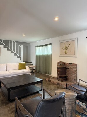 A modern living room with a staircase, a fireplace, and a sofa.