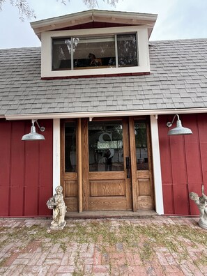 A building with a red exterior, a wooden front door, and a small balcony above the entrance. - Welcome to the Red Barn House: 3BR 2BA country living in Santa Ynez Valley (Santa Ynez)