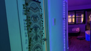 Um corredor com uma porta decorativa, um respiradouro na parede e uma janela com persianas.