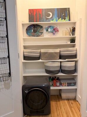 A laundry room with a washing machine, shelves with baskets, and a painting on the wall. - Artist's Apartment in Manhattan (New York)